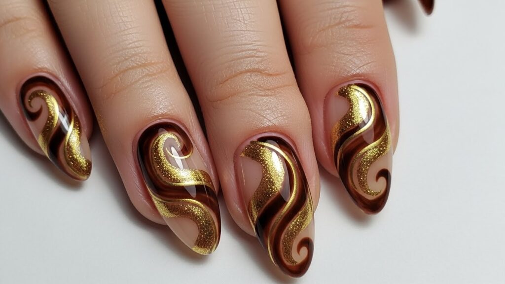 Brown and gold swirl almond nails for fall 2025.