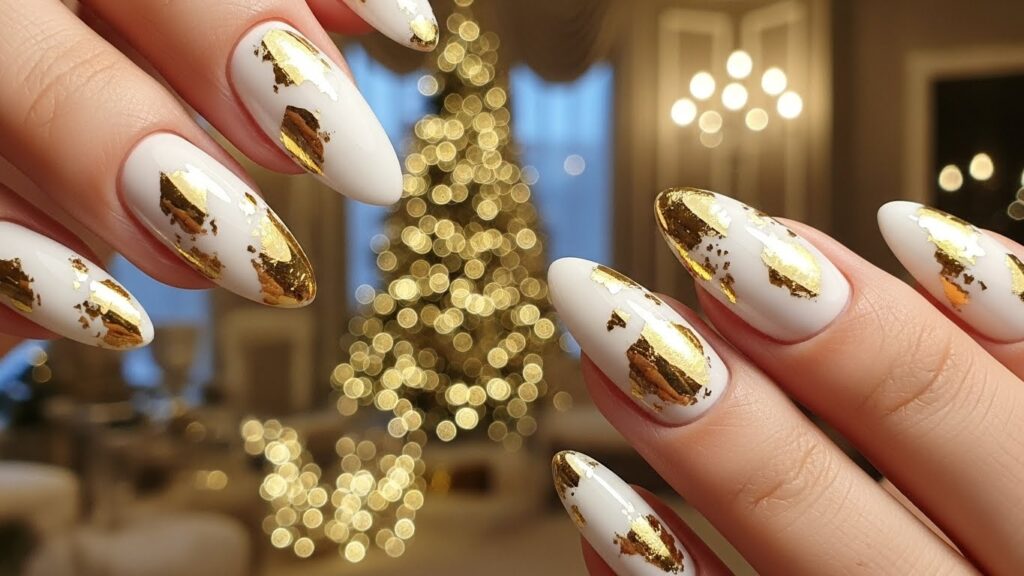 White Christmas nails decorated with shiny gold foil accents.