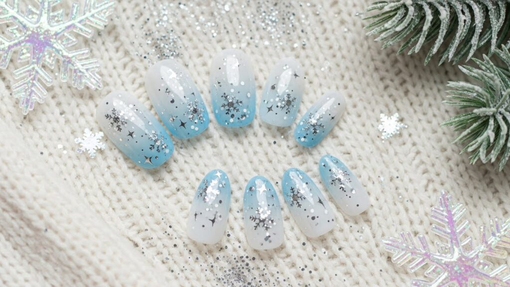 Glitter snowflake nails with silver sparkles and winter aesthetic.